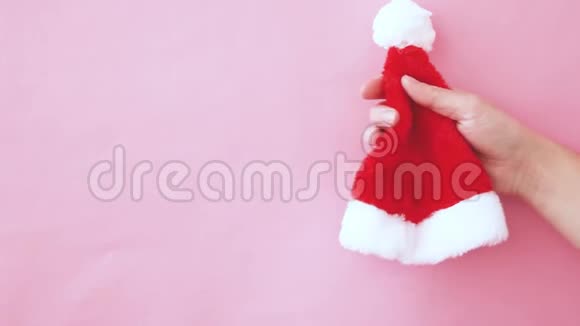 简单的最小设计女性手按挤压圣诞圣诞圣诞老人的帽子隔离粉红色的粉彩五颜六色的时尚视频的预览图
