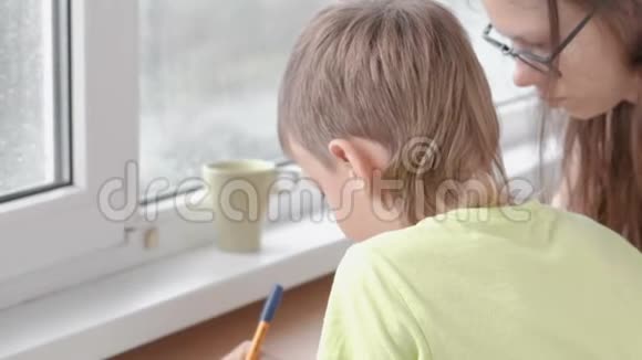 男孩学会坐在桌子旁写信和老师导师一起做作业视频的预览图