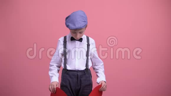 小男孩穿着老式的衣服试图修复红色破碎的玩具心未回报的爱视频的预览图