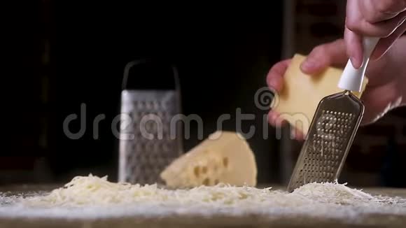奶酪慢慢地在木桌上的金属磨碎器上摩擦有很多被磨碎的儿子慢动作烹饪原料的概念视频的预览图