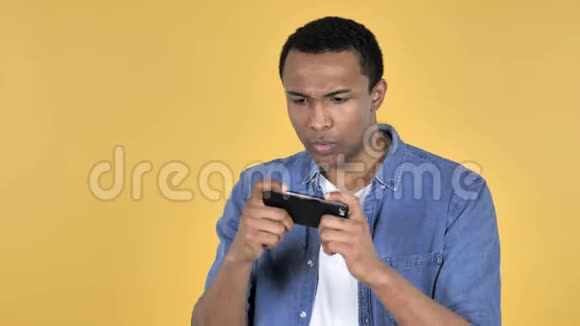 非洲年轻人玩智能手机游戏黄色背景视频的预览图