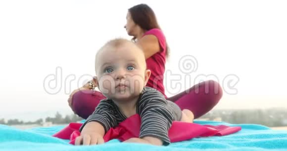 可爱的婴儿靠近妈妈做瑜伽视频的预览图