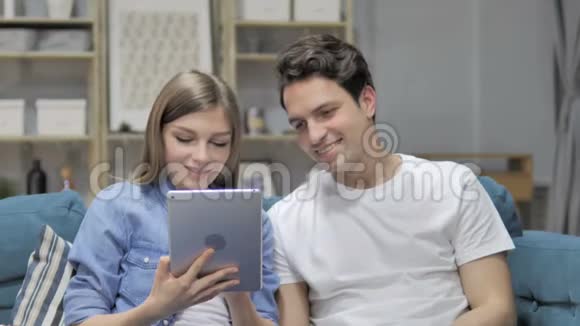 年轻夫妇在餐桌上浏览互联网而在沙发上放松视频的预览图