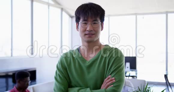 一位英俊的亚洲男性高管双臂交叉站在现代办公室视频的预览图
