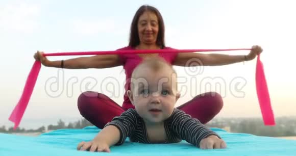 可爱的婴儿躺在附近的女人做瑜伽视频的预览图