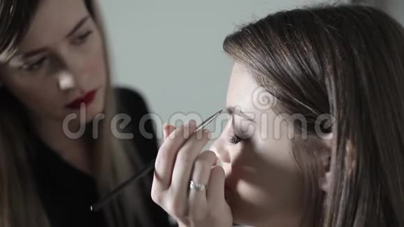 化妆师为眉毛化妆年轻女孩做专业化妆修眉视频的预览图