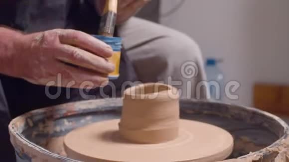一个人在陶轮上给罐子上色视频的预览图