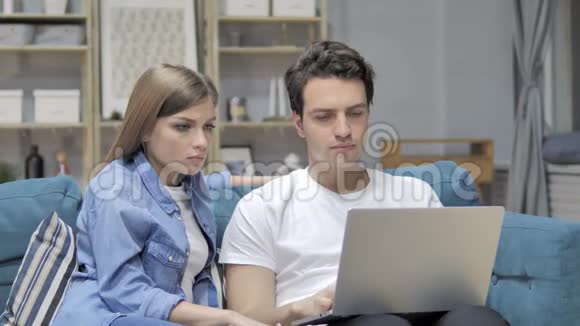 沮丧不快乐的年轻夫妇面对笔记本电脑的损失视频的预览图