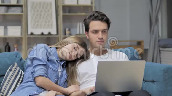快乐男在睡觉的时候用手提电脑女朋友的头靠在肩膀上视频的预览图