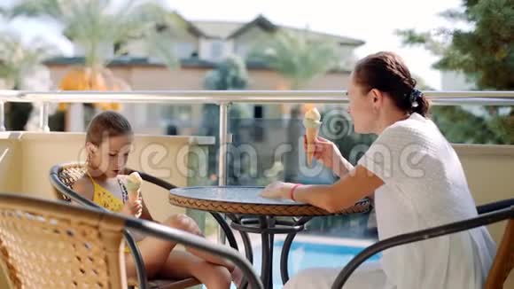 一个女人带着一个小女儿坐在阳台上的桌子上吃冰淇淋视频的预览图