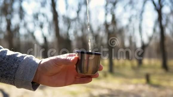 把热茶从热水瓶里倒入杯子里在森林里野餐大自然视频的预览图