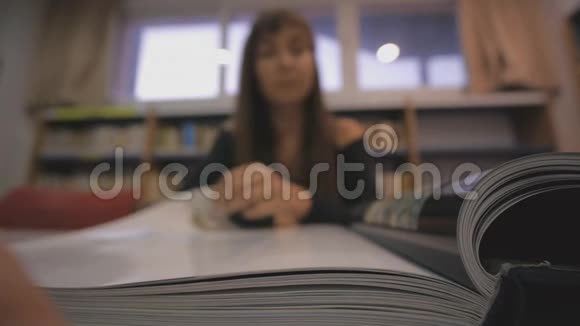 年轻的高加索女人在图书馆翻着插图书籍的一页专注于书脊视频的预览图
