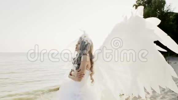 美丽美丽的金发女郎与天使的翅膀海滨视频的预览图