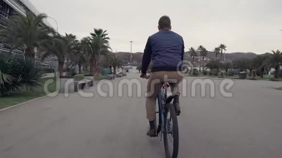 夏天男人骑着自行车在热带城市的马路上骑着自行车视频的预览图