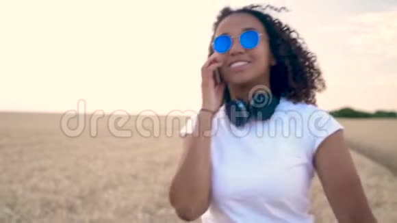非洲裔美国混血青少年在日落时分用手机戴着太阳镜说话视频的预览图