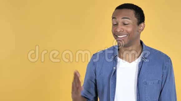 非洲青年男子在侧面展示产品黄色背景视频的预览图