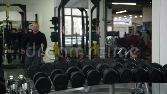 健美运动员带着沉重的哑铃照镜子做运动视频的预览图