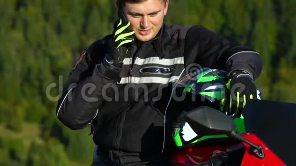 一个骑摩托车的人带着摩托车在山上的年轻帅哥他正站在摩托车旁边视频的预览图