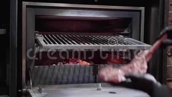 厨师双手戴着黑色手套把大块的肉放在教授用的炭烤箱里烤视频的预览图