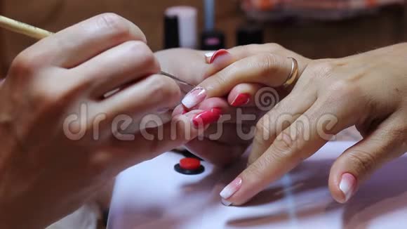 美甲大师手中握着美丽的女人的无名指用特殊的工具调整指甲上的莱茵石指甲艺术视频的预览图