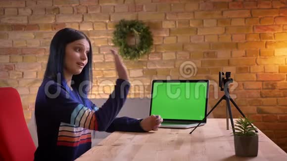 年轻迷人的时尚女性视频博客作者使用带有绿色笔记本电脑在镜头上直播的特写镜头视频的预览图