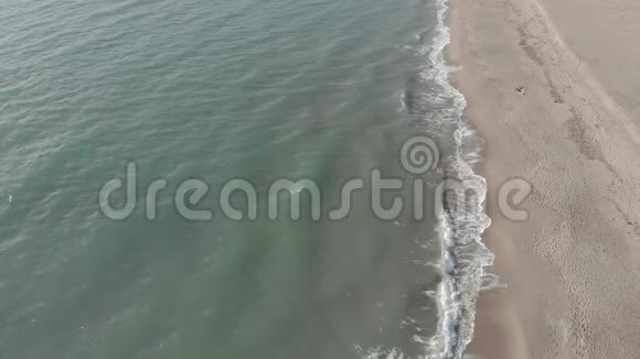 空中景色飞过海岸线海浪拍打着泡沫撞击着沙滩视频的预览图