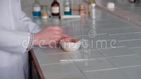 穿着白色外套的女孩在一个特殊的盘子里搅拌化学溶液视频的预览图