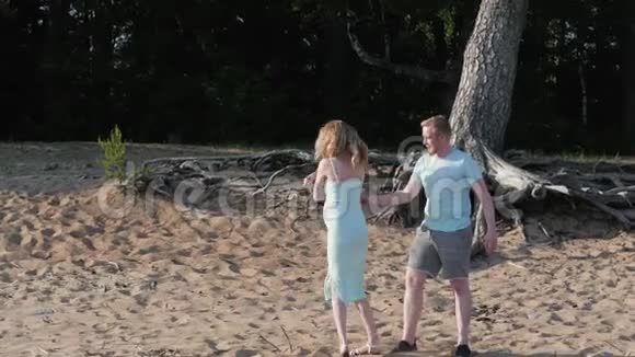 年轻的孕妇和丈夫走在海边一家人期待着一个婴儿沿着海岸散步怀孕了视频的预览图