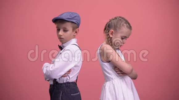 伤心的孩子在争吵之后默默地站在后面孤立的粉红色背景视频的预览图