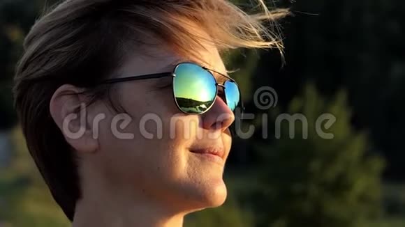一个戴着太阳镜的女人在刮风的天气里慢吞吞地站在森林里视频的预览图