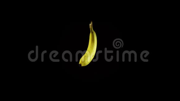 孤立的成熟香蕉在水的喷雾下旋转在黑色的背景上视频的预览图