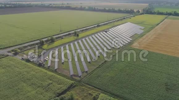在日落时用太阳能电池板在绿色的田野里绕着田野飞行太阳能电池板清洁可再生能源视频的预览图