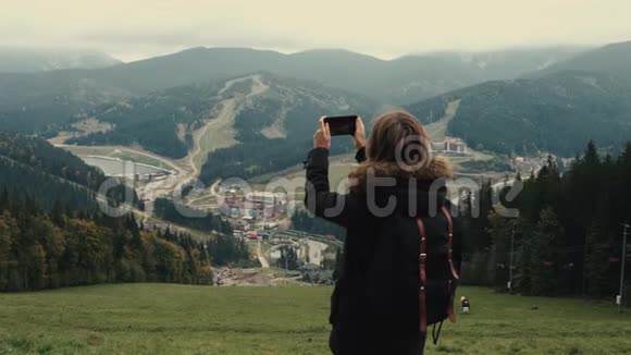 年轻女孩徒步旅行者正在手机相机上拍摄美丽的雾山景观视频视频的预览图