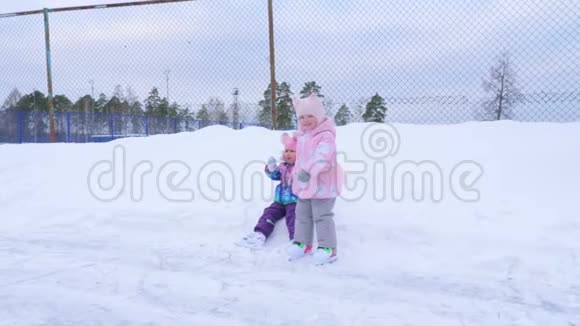 穿着鲜艳衣服的可爱有趣的小女孩学会在溜冰场上滑冰视频的预览图