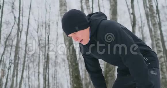 一个年轻人在冬天的森林里晨跑累了停下来休息继续跑他恢复了体力视频的预览图