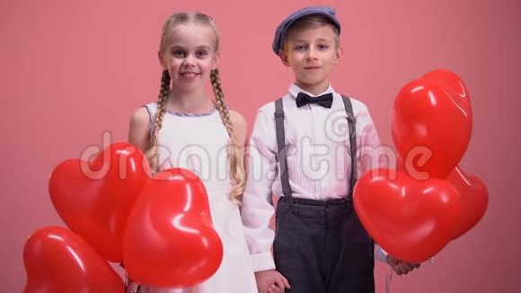 几个可爱的孩子带着红心气球对着镜头微笑情人节视频的预览图