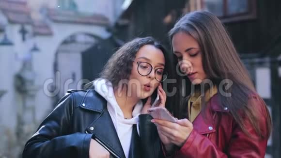 两个女孩在户外使用智能手机两名女性共享智能手机数据或联系人视频的预览图