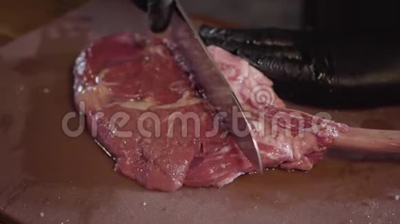 双手戴黑色乳胶手套在骨头上切开大块生肉视频的预览图