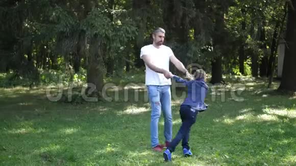 年轻的父亲和他的儿子在秋天的公园里旋转快乐的玩耍和欢笑动作缓慢4K视频的预览图