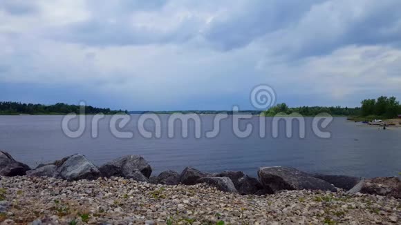 在阴云密布的天空下与人和船一起观赏湖景湖岸和水视频的预览图