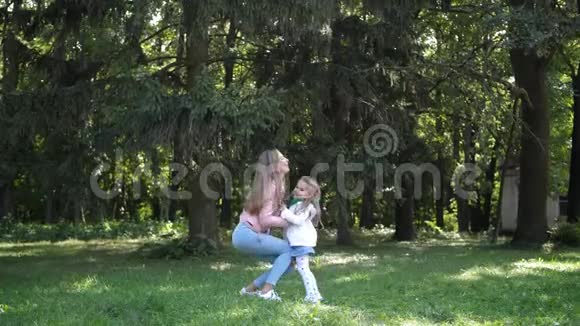 年轻的母亲把她的女儿扔到秋天的公园里在和她女儿玩4k慢动作视频的预览图