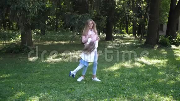 年轻的母亲在秋天的公园里和孩子一起旋转和女儿开心的玩耍和欢笑慢动作4K视频的预览图