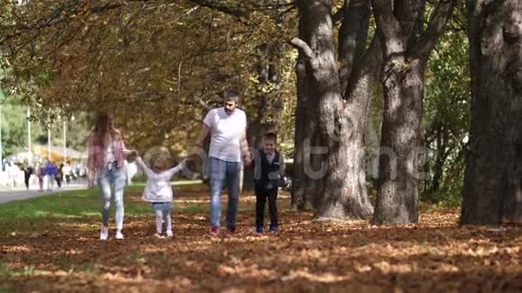 在秋天的一天幸福的一家人沿着公园的小巷散步4K慢动作视频的预览图