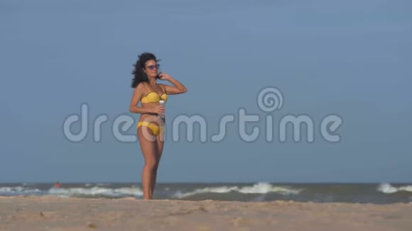 太阳眼镜中的女人把头发随风飘摇在沙滩上捧着一瓶水视频的预览图