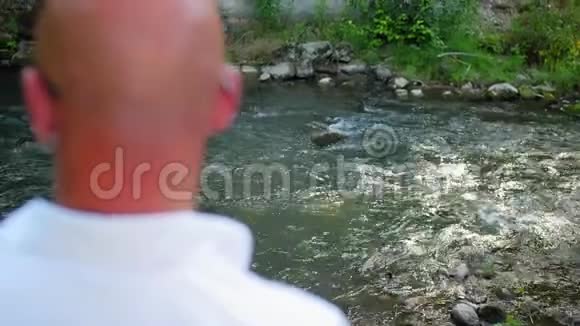 后景一个秃头男人看着一条河在桥下流淌近距离射击视频的预览图