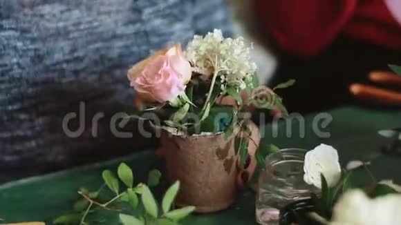 花店老板手里拿着一个小罐子里面放着美丽的粉红色和白色的花桌子上放着工作后的残花视频的预览图