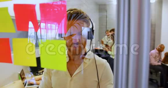 男性高管在头戴式耳机边看着4k便签视频的预览图