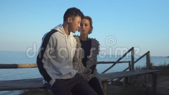 恋爱中的跨种族年轻夫妇在湖底阳光下坐在木凳上自拍视频的预览图