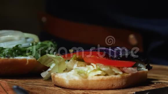 用酱汁蔬菜西红柿和厨师的手将大虾加入到其他配料中特写汉堡包股票视频的预览图