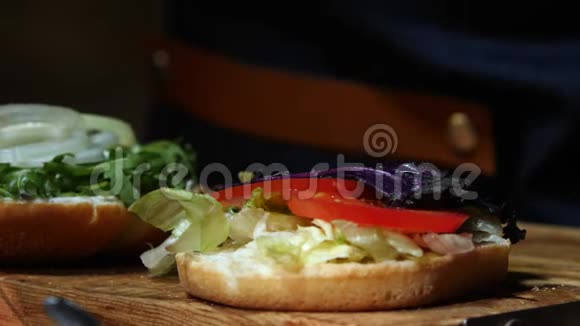 用酱汁蔬菜西红柿和厨师的手将大虾加入到其他配料中特写汉堡包股票视频的预览图